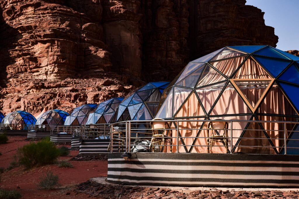 A row of geodesic dome cabins against a dramatic rocky desert backdrop.