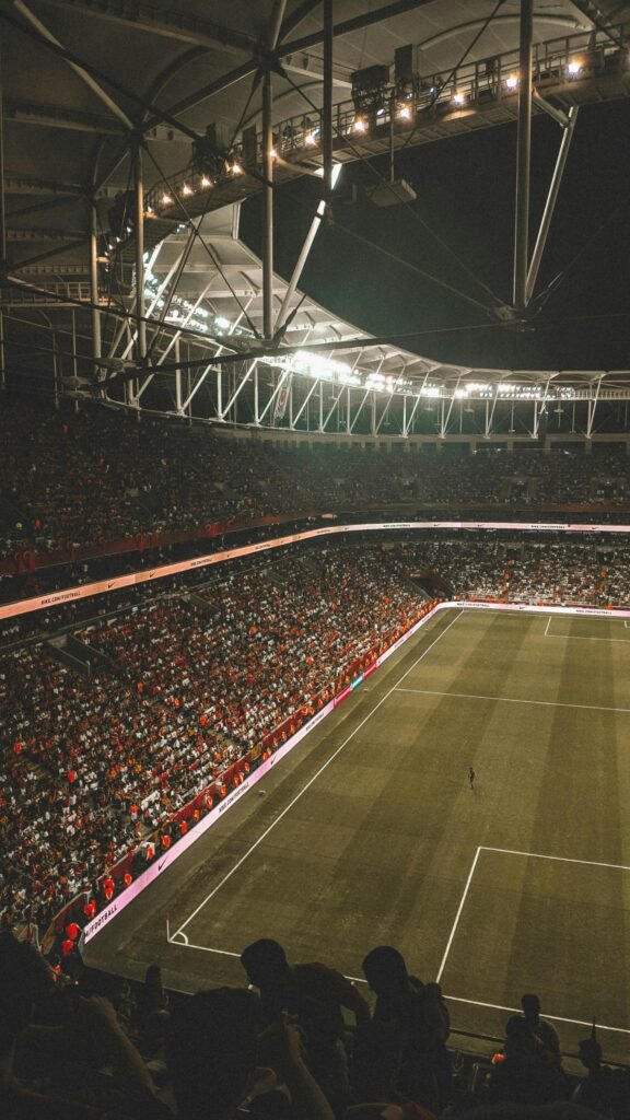 A vibrant night soccer match with a full audience in an illuminated stadium.