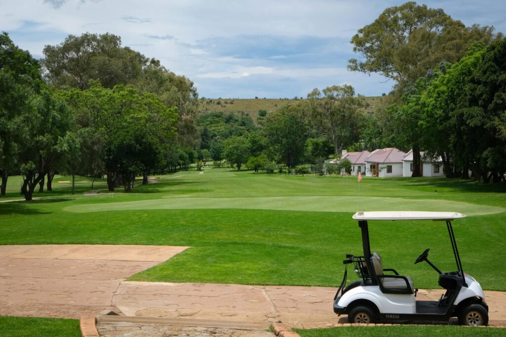 A tranquil scene of a golf course with a cart under a clear blue sky.