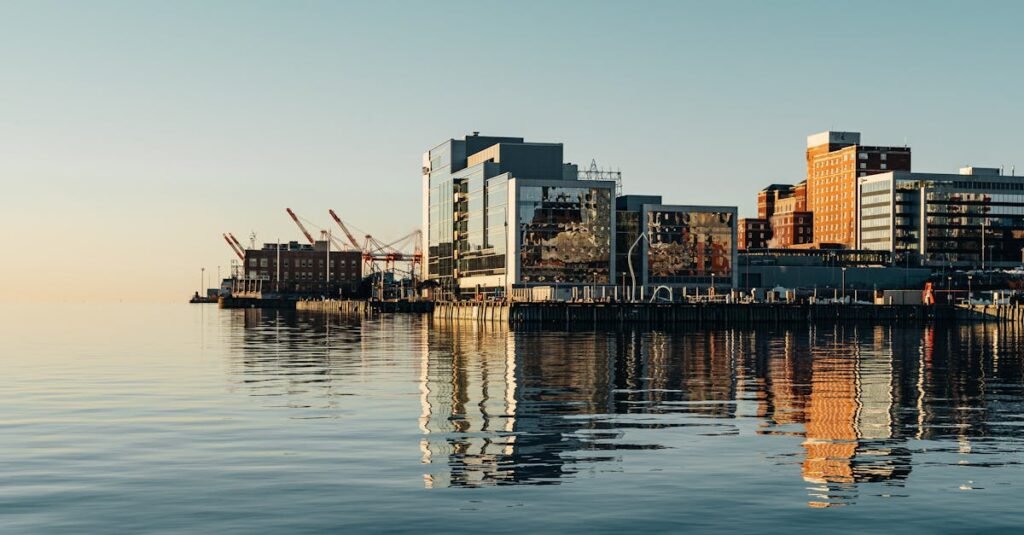 A serene view of Halifax waterfront with modern buildings reflecting on the water under a clear sky.