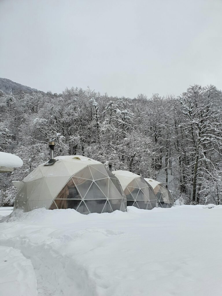 Geodesic domes covered in snow in a serene winter landscape at Krasnaya Polyana.